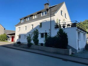 A two-story building with a red door, multiple windows, and a balcony. - Apartment 'Sauerland 2' with Mountain View, Balcony and Wi-Fi (Willingen (Upland))