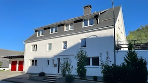 En tvåvåningsbyggnad med en vit fasad, flera fönster och en röd garageport.