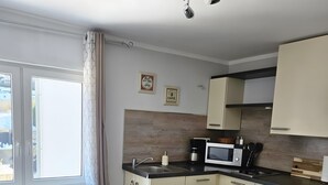 A modern kitchen with a dining table, a coffee machine, and a microwave. - Apartment 'Sauerland 3' with Mountain View and Wi-Fi (Willingen (Upland))