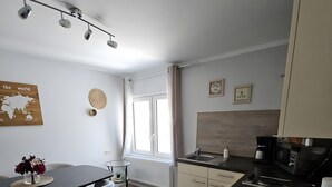 A modern kitchen with a dining area, featuring a black countertop, white cabinets, and a world map decoration. - Apartment 'Sauerland 3' with Mountain View and Wi-Fi (Willingen (Upland))