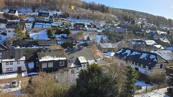 Un área residencial con casas, algunas con nieve en los techos, y una colina al fondo.