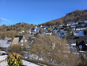 Ein Wohngebiet mit Häusern an einem Hang, einige mit Schnee auf den Dächern.