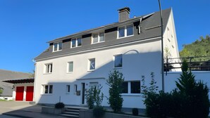A two-story building with a white facade, multiple windows, and a red garage door. - Apartment 'Sauerland 3' with Mountain View and Wi-Fi (Willingen (Upland))