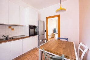 Eine Küche mit weißen Schränken, einem Holztisch und einer gelben Pendelleuchte.