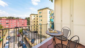 Un balcó amb taula i cadires, amb vista a una zona d'aparcament i edificis.