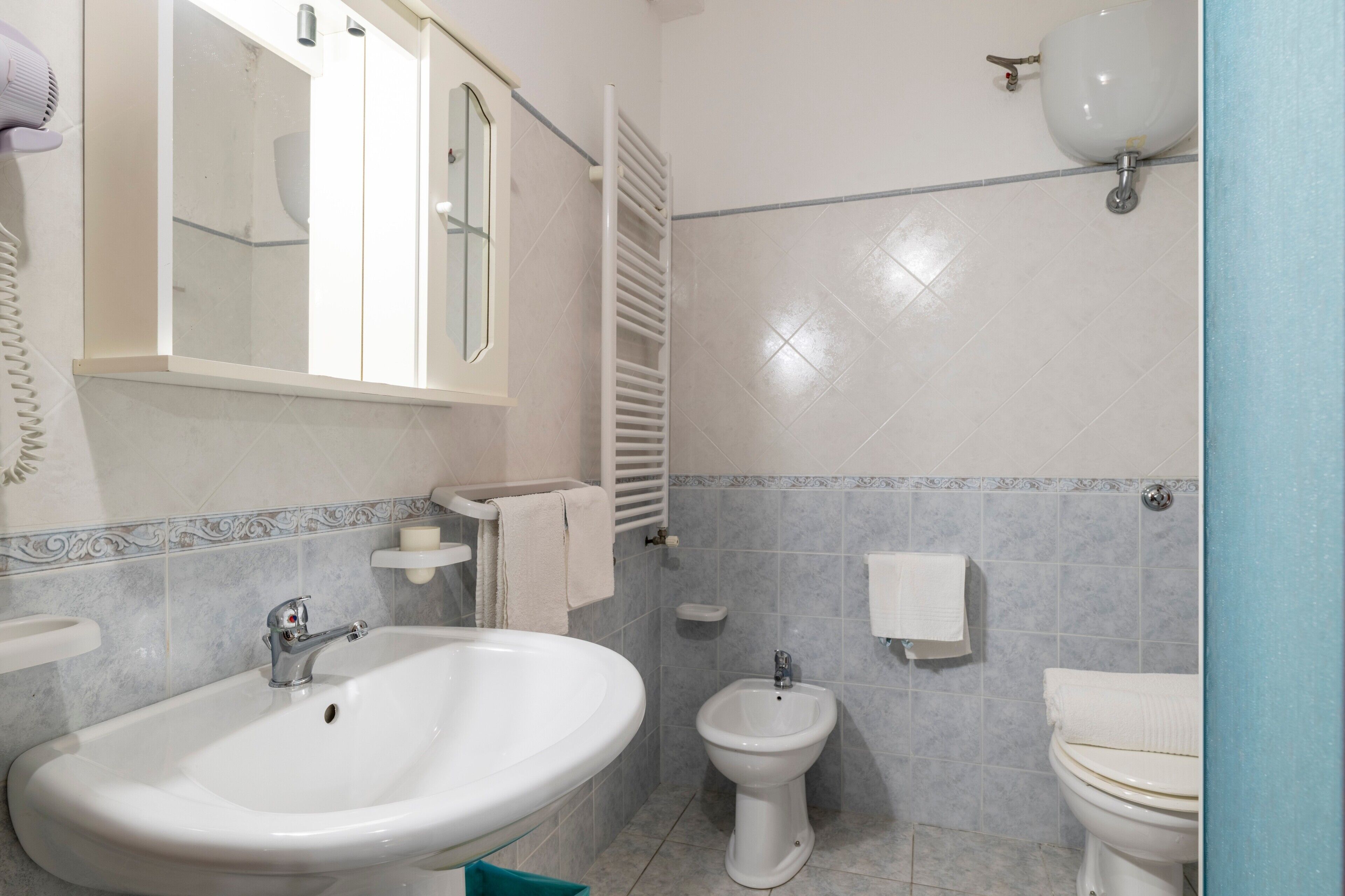 Casa de banho com lavatório, bidé, sanita e porta-toalhas.