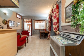 A room with a wooden counter, red sofa, dining table, and a vintage radio.
