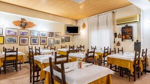 A restaurant with multiple tables, chairs, and framed pictures on the walls. - Double Room 205 with Air Conditioning (Jerzu)