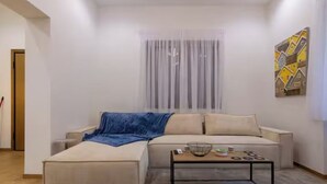 A modern living room with a sofa, ottoman, and a coffee table. - Timeless 1 bedroom Luxury at Panathenaic Stadium (Athina)
