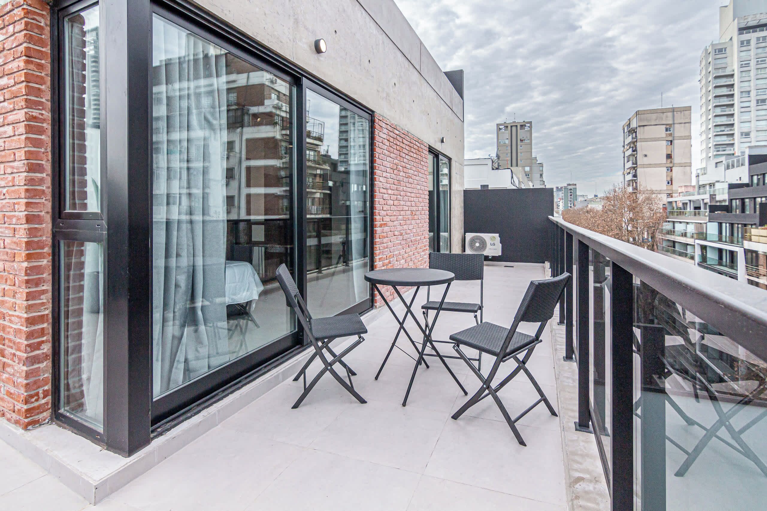 A balcony with a glass door, a round table, and two chairs.