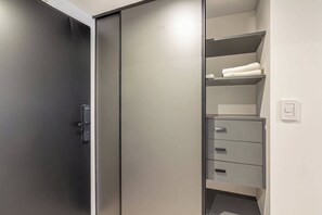 A modern closet with sliding doors, a shelf with folded towels, and a drawer unit. - Soho Village en Palermo by Magno | 102 (Buenos Aires)