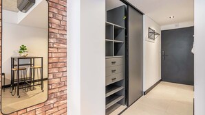 Ein Zimmer mit Backsteinwand, einem Spiegel, einem Tisch mit Hocker und einem Schiebetürenschrank.