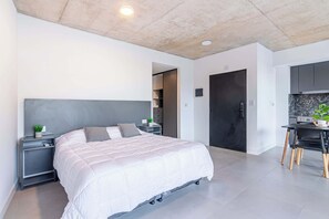 A modern bedroom with a bed, bedside tables, a desk, and a door. - Soho Village en Palermo by Magno | 404 (Buenos Aires)