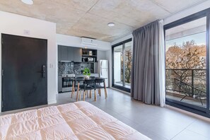 Une chambre moderne dotée d’un grand lit, d’une kitchenette et d’un balcon avec vue.
