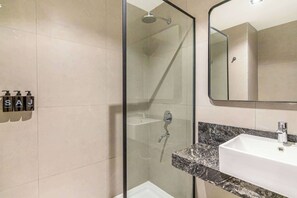 A modern bathroom with a glass-enclosed shower, a white sink, and a mirror above it. - Soho Village en Palermo by Magno | 401 (Buenos Aires)