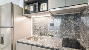 Een keuken met een roestvrijstalen koelkast, een ingebouwde magnetron, een broodrooster en een zwart inductiekookplaat.