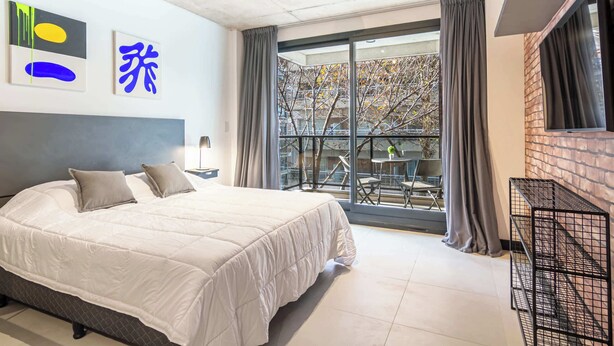 Een moderne hotelkamer met een groot bed, een balkon met uitzicht en een accentmuur van baksteen.