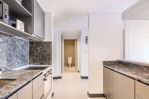 Eine moderne Küche mit Granit Arbeitsplatten, einem Einbauofen und Blick ins angrenzende Badezimmer.