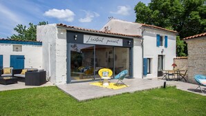 A modern building with a glass storefront, outdoor seating, and a well-maintained lawn.