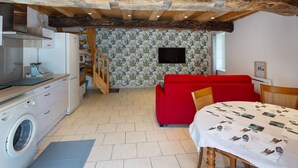 A kitchen with a washing machine, a red sofa, and a dining table with a placemat.