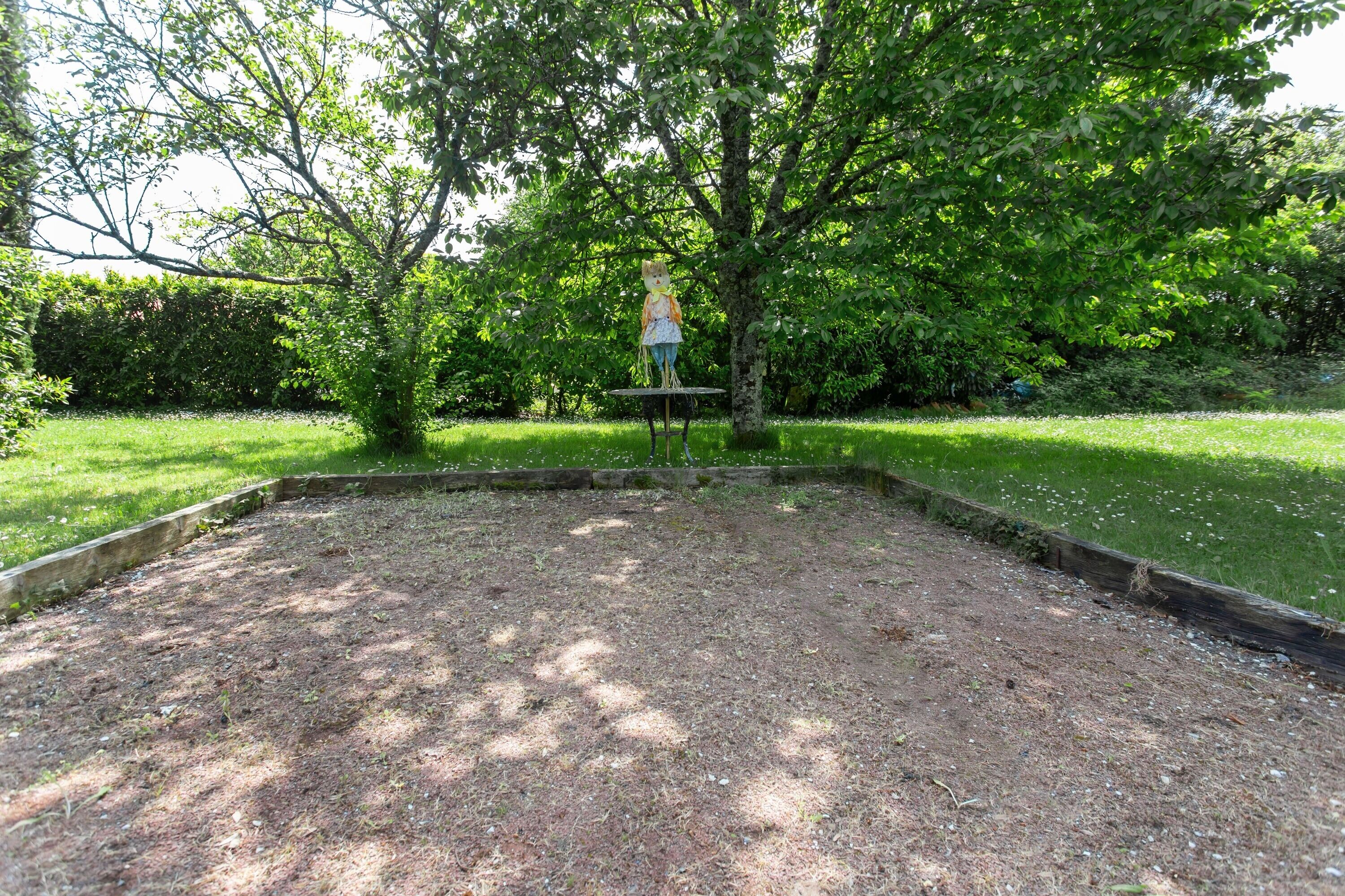 Un jardí amb un arbre, un gandul i una taula petita.