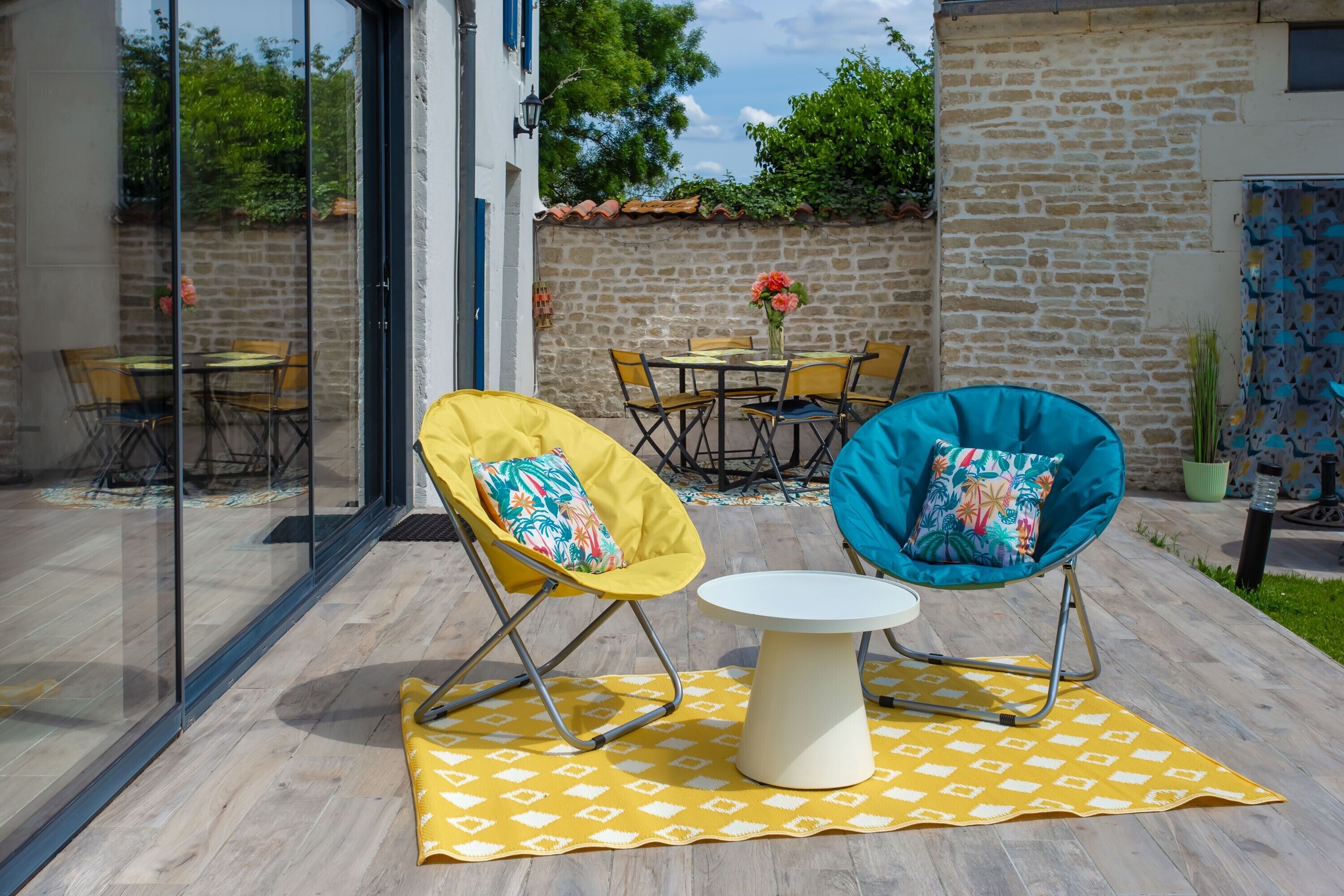 Une terrasse avec deux chaises, une table et une porte vitrée donnant sur un coin repas.