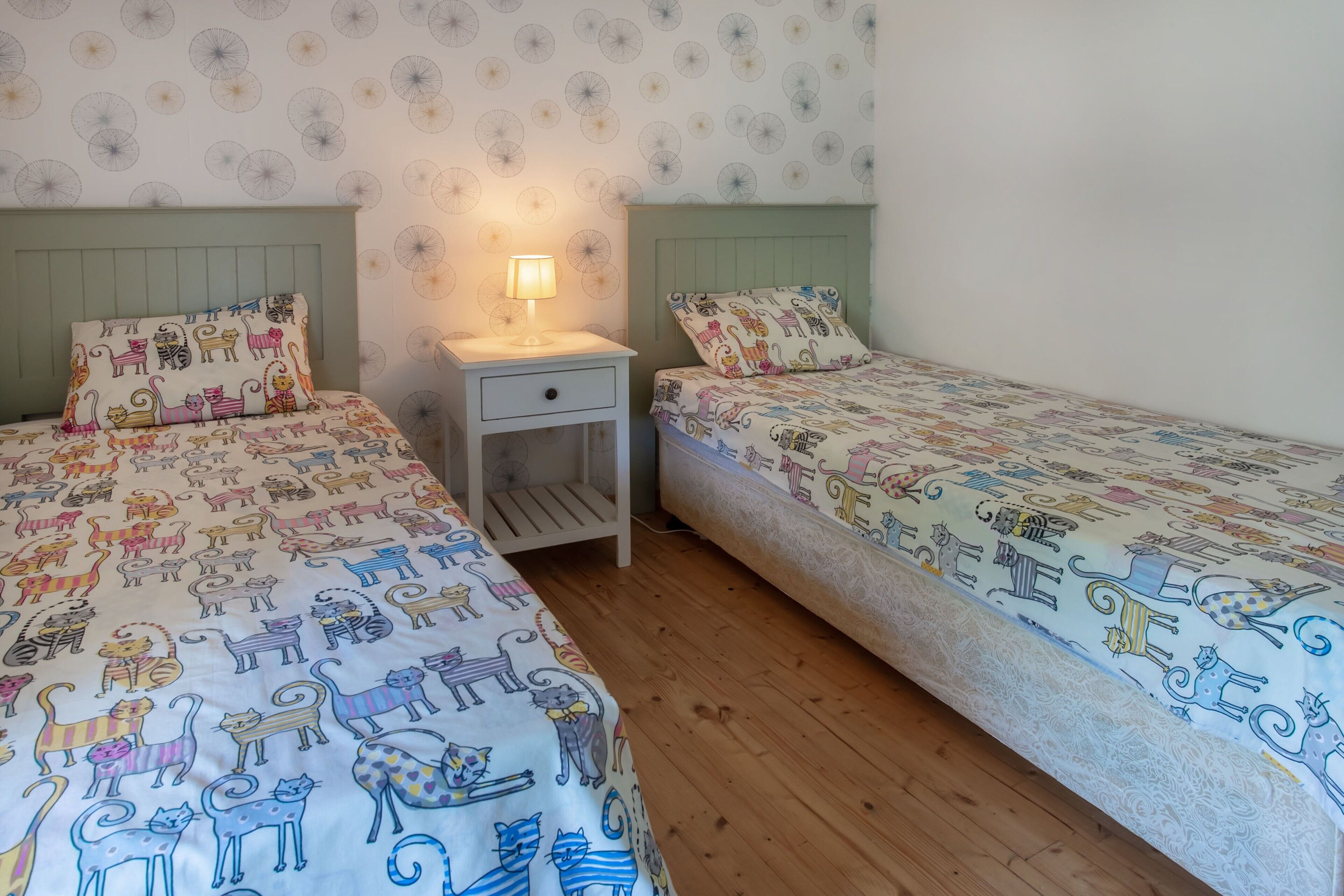 A bedroom with two beds, a nightstand, and a wall with a circular pattern.