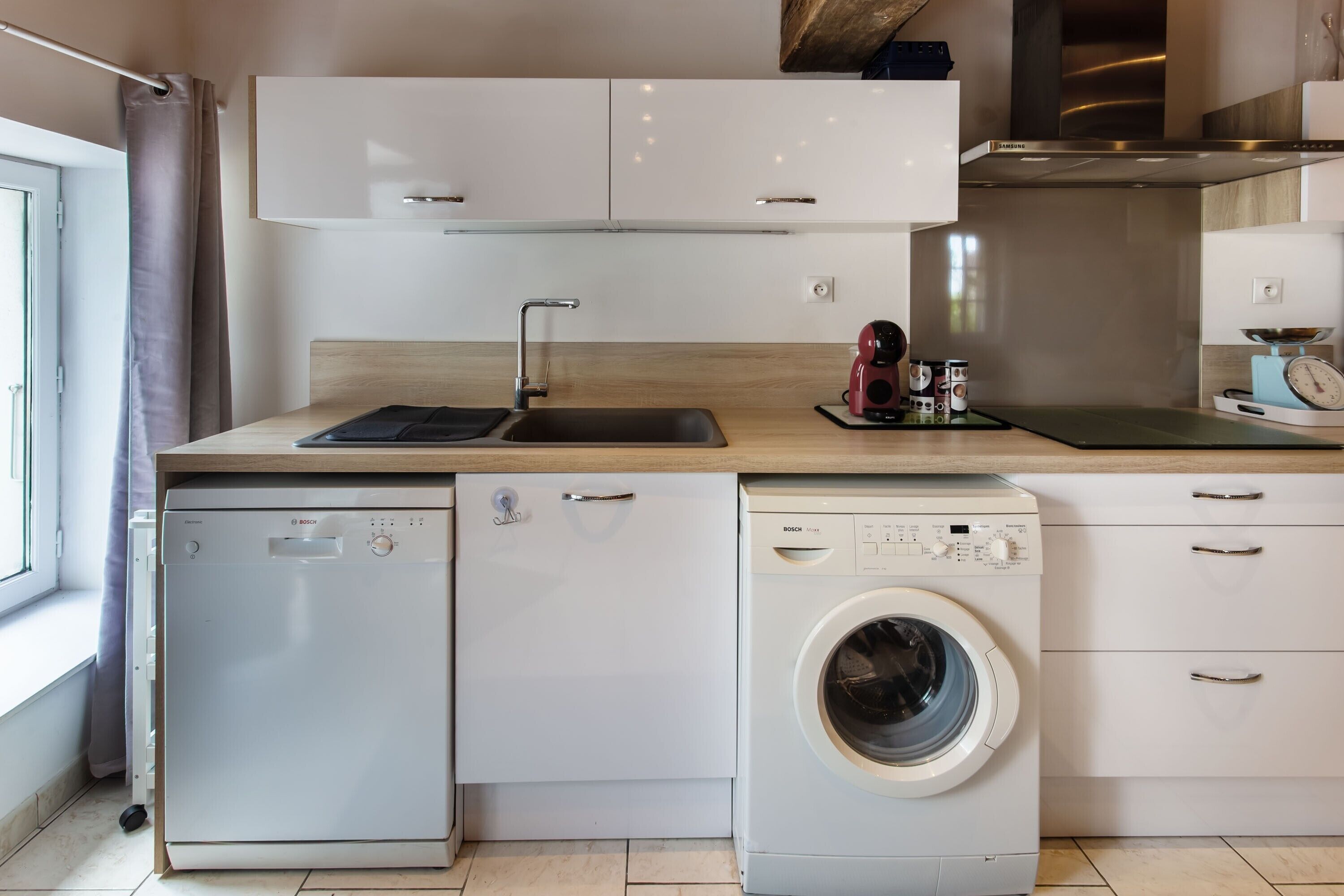 A compact kitchen with a dishwasher, washing machine, and a sink.