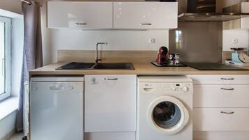 A compact kitchen with a dishwasher, washing machine, and a sink.
