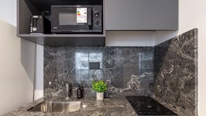Una cocina con encimera de granito, microondas integrado, fregadero y una pequeña planta en maceta.