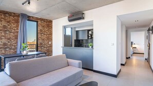 A modern living room with a sofa, a dining table, and a kitchen area with a built-in oven. - Soho Village en Palermo by Magno | 802 (Buenos Aires)