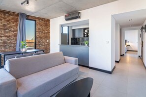 A modern living room with a sofa, a dining table, and a kitchen area with a built-in oven. - Soho Village en Palermo by Magno | 802 (Buenos Aires)