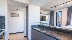 A modern kitchen with a marble countertop, grey cabinets, and a built-in oven. - Soho Village en Palermo by Magno | 802 (Buenos Aires)