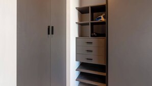 Een moderne garderobe met meerdere lades, planken, een kledingroede en een deur met een handgreep.