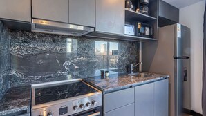 Een moderne keuken met een roestvrijstalen fornuis, een granieten aanrecht en ingebouwde apparatuur.
