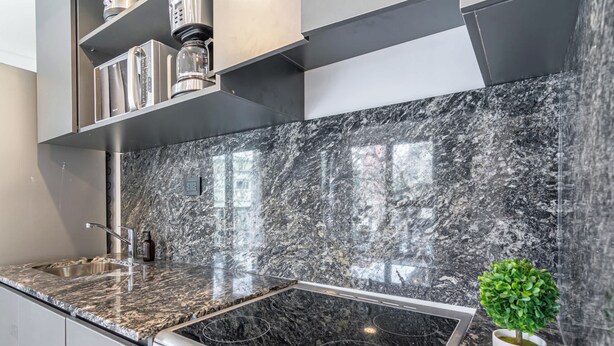 A kitchen with a black marble backsplash, stainless steel appliances, and a small potted plant. - Soho Village en Palermo by Magno | 203 (Buenos Aires)