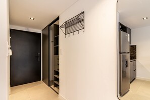 A modern kitchen with a built-in refrigerator, a black door, and a white wall with a metal rack. - Soho Village en Palermo by Magno | 602 (Buenos Aires)