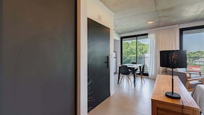 Ein modernes Zimmer mit einem Holztisch, einem Flachbildfernseher und einer Essecke mit Stühlen und Tisch.