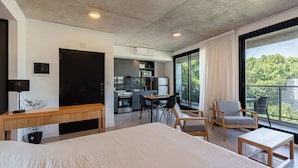 Ein modernes Hotelzimmer mit einem großen Bett, einem Schreibtisch, einem Essbereich und einer Küchenzeile.
