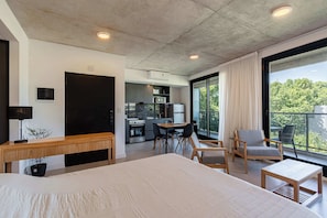 A modern hotel room with a large bed, a desk, a dining area, and a kitchenette. - Soho Village en Palermo by Magno | 504 (Buenos Aires)