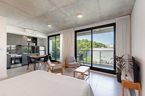 Et moderne hotelværelse med en stor seng, et spiseområde, et tekøkken og en balkon med udsigt.