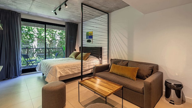Ein modernes Schlafzimmer mit Bett, Sofa und einem kleinen Tisch.
