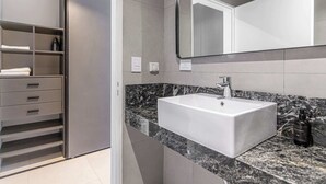 Un baño moderno con un lavabo blanco, un espejo grande y una encimera de mármol.