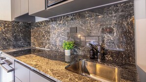 Cocina con encimera de granito, pileta de acero inoxidable y microondas sobre la encimera.