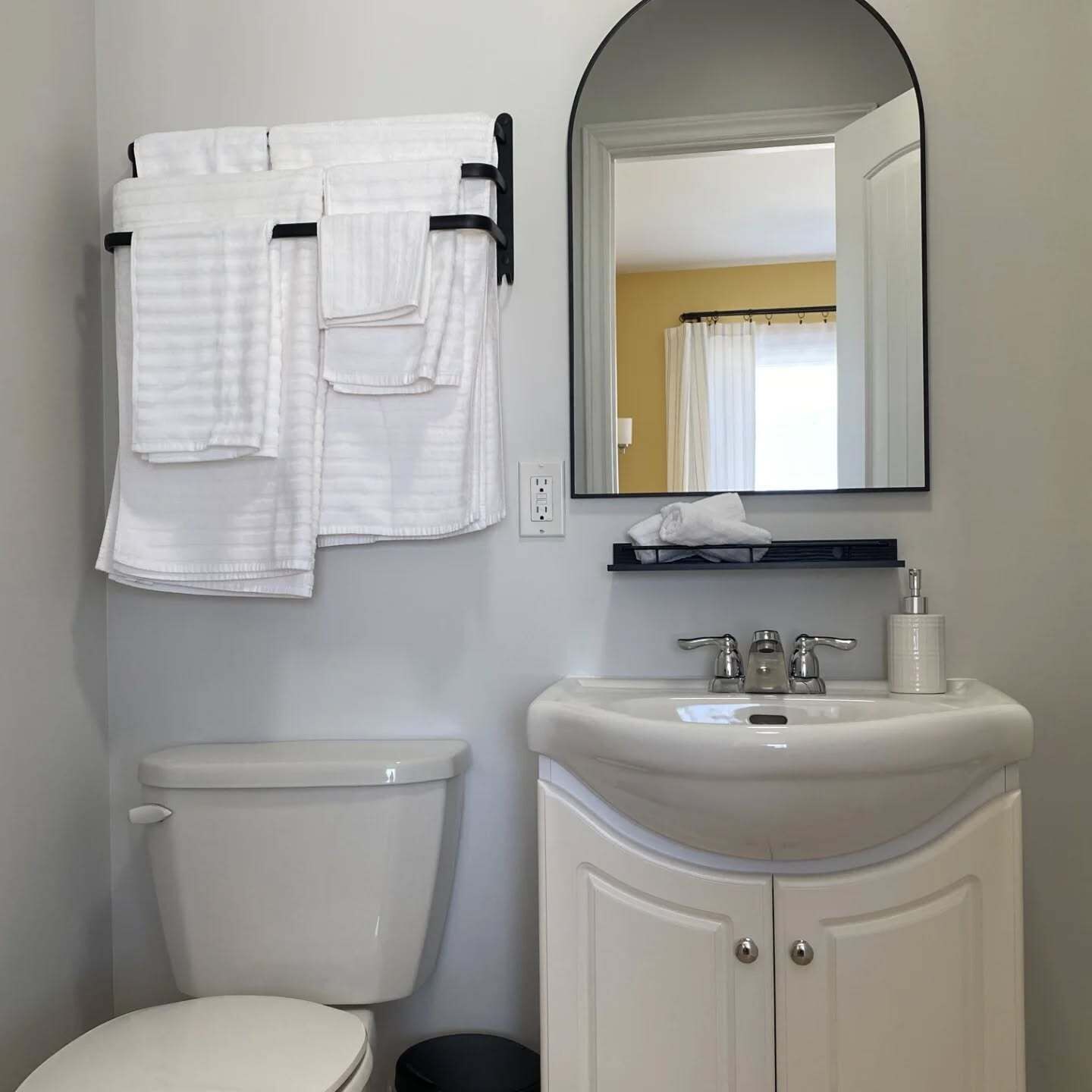 Une salle de bain avec des toilettes, un lavabo et un miroir.