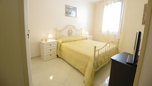 A bedroom with a bed, bedside tables, a lamp, a TV, and a window with curtains. - Case Vacanza Edera - Orchidea near Trapani Port (Trapani)