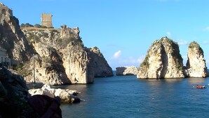 A coastal landscape with rocky cliffs, a clear blue sea, and a small boat. - Case Vacanza Edera - Orchidea near Trapani Port (Trapani)