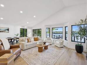 A spacious living room with a large window overlooking a lake, a dining area with a table and chairs, and a seating area with sofas and a coffee table. - *Rare* Lake Luxury-Sleeps 32, 10 Bedrooms, 2 Docks (Winchester)