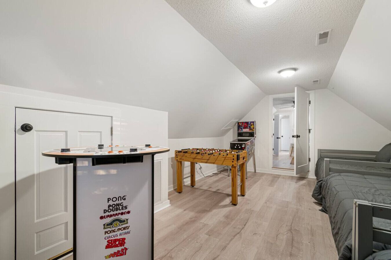 A room with a ping pong table, a foosball table, and a bed.