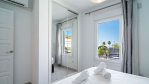 Une chambre d’hôtel avec un lit, une grande fenêtre, un miroir et une porte.